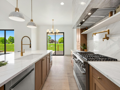 Modern kitchen with marble countertops, brass fixtures, and large windows